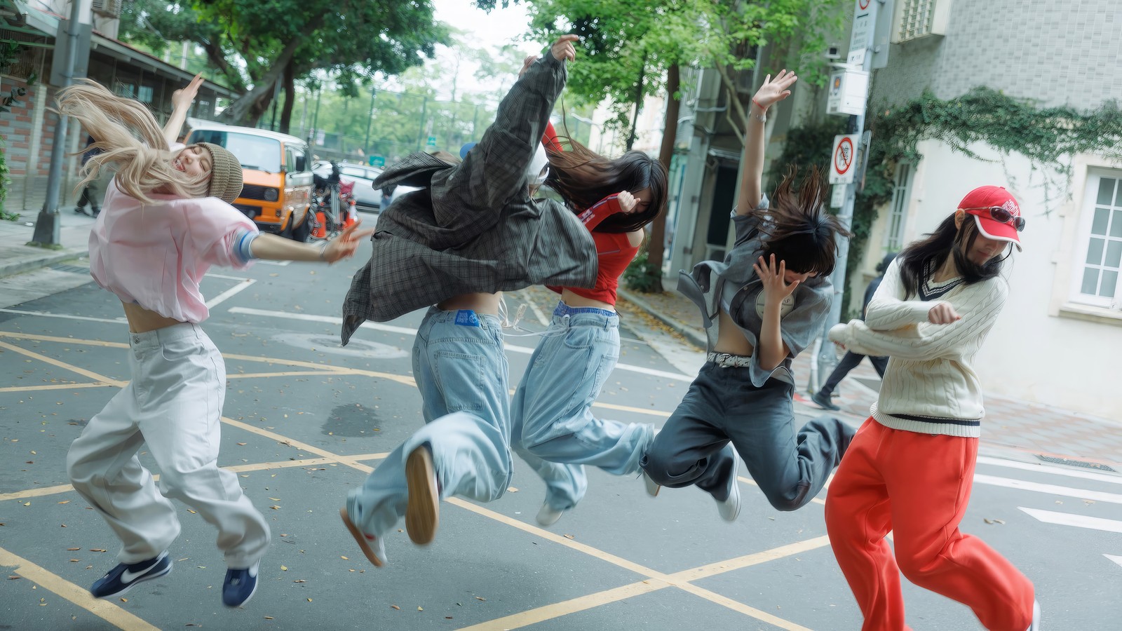 Four people jumping in the air in the middle of a street (newjeans, kpop, new jeans, korean girl group, k pop)