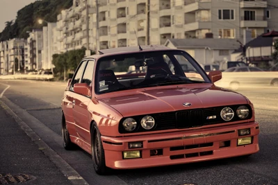 Clássico BMW M3 E30 em laranja vibrante, exibindo estética esportiva em uma rua da cidade.