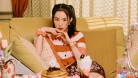 Irene from Red Velvet in a cozy setting surrounded by desserts and soft lighting.