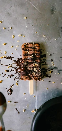 Popsicle de glace au chocolat décadent arrosé de sauce au chocolat riche et saupoudré de noix concassées.