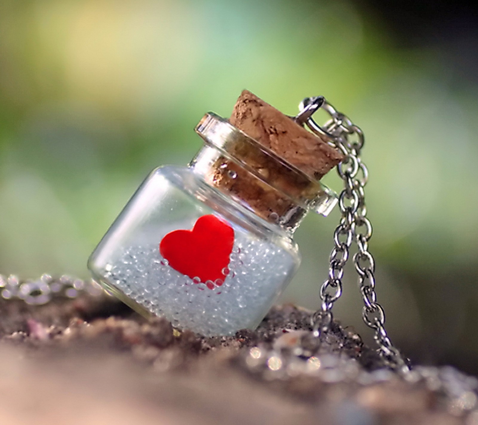 There is a small glass bottle with a red heart inside (bottle, heart, love)