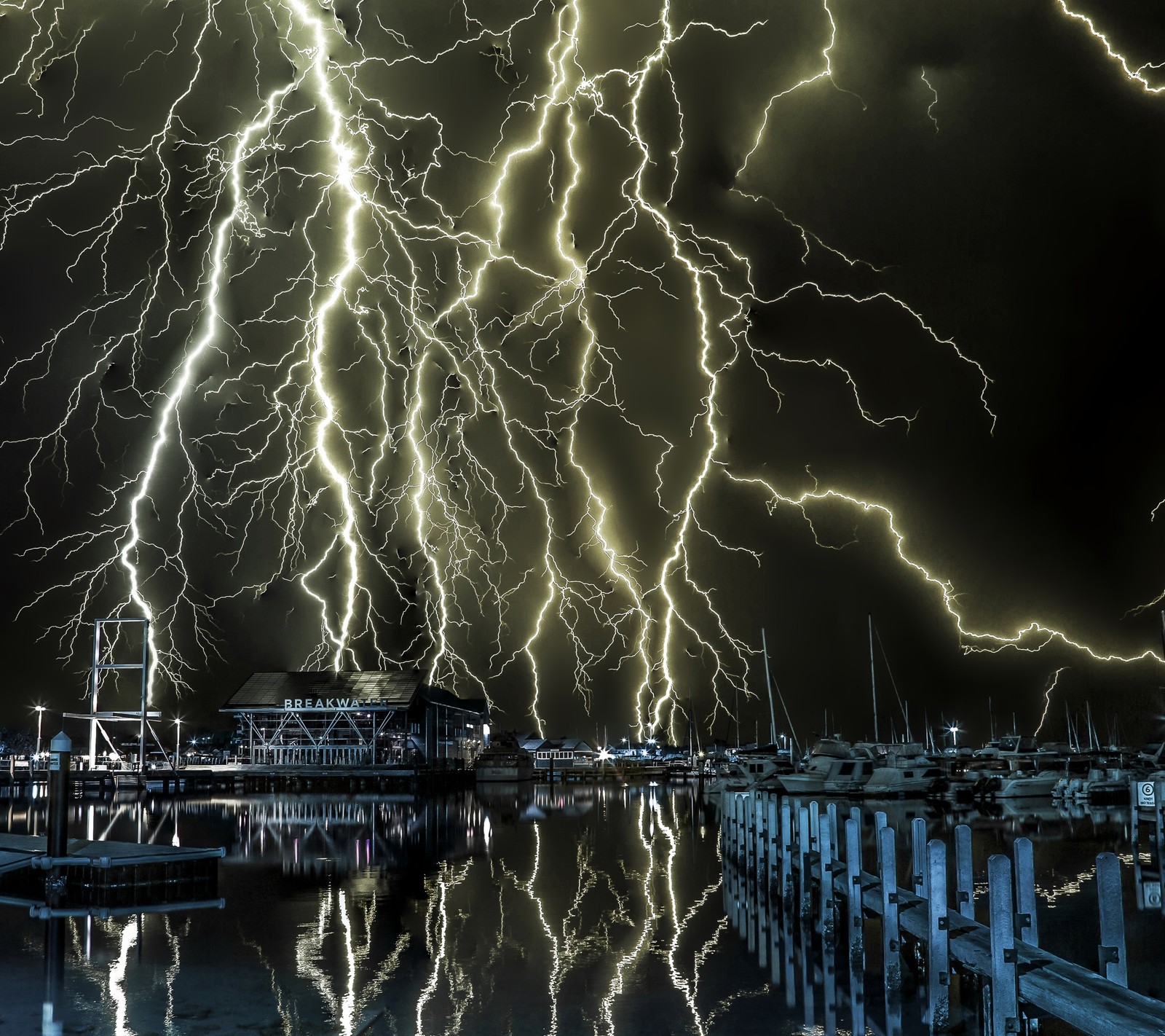 Lightning strikes over a marina at night with boats in the water (boat, bolt, dock, electric, lightning)