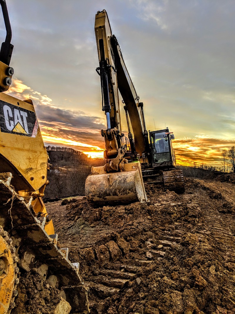 There are two large machines that are sitting in the dirt (caterpillar excavator 336, excavating, 336)