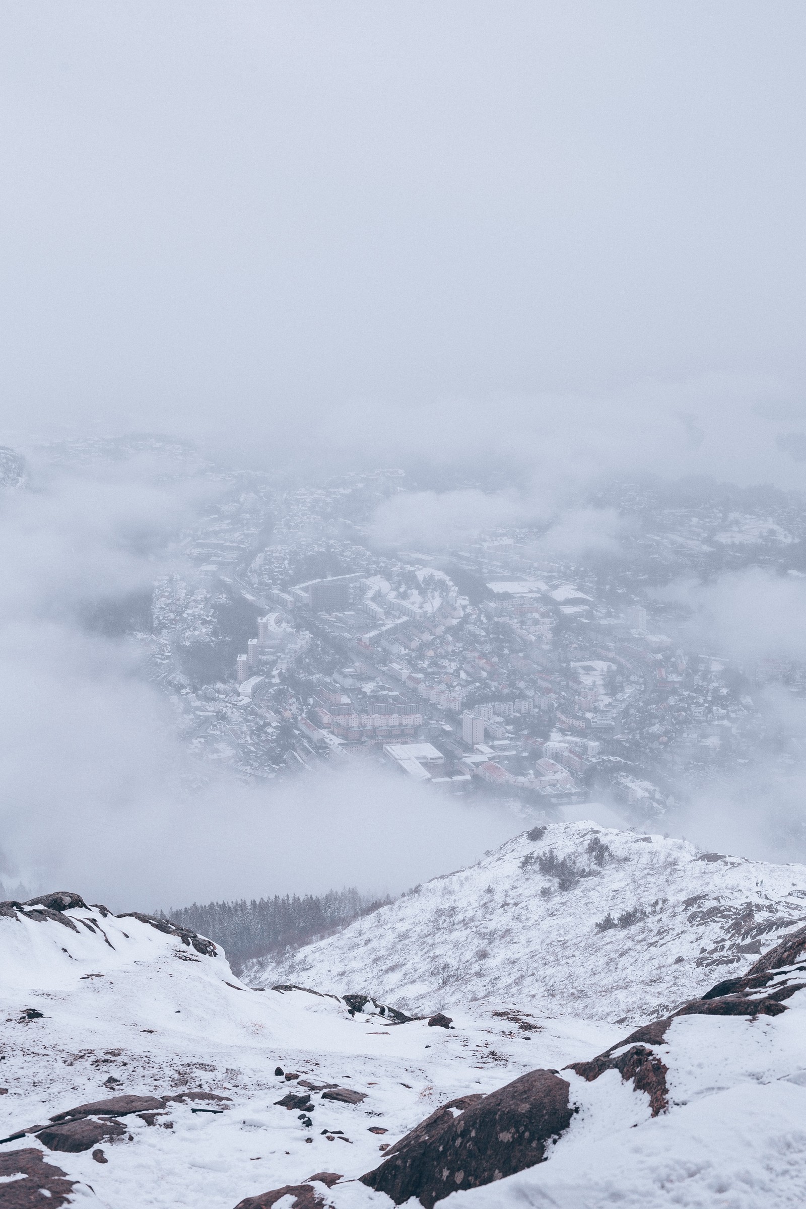 Skifahrer auf einem schneebedeckten berg mit einer stadt im hintergrund (gefrieren, schnee, gebirgige landformen, gefallen, winter)