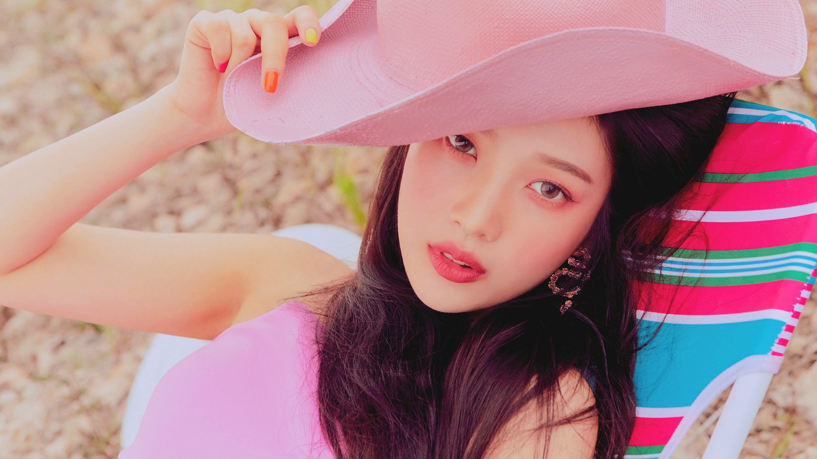 Una mujer alta con un sombrero rosa sentada en una silla de playa (red velvet, alegría, park soo young, el festival reve día 2, the reve festival day 2)