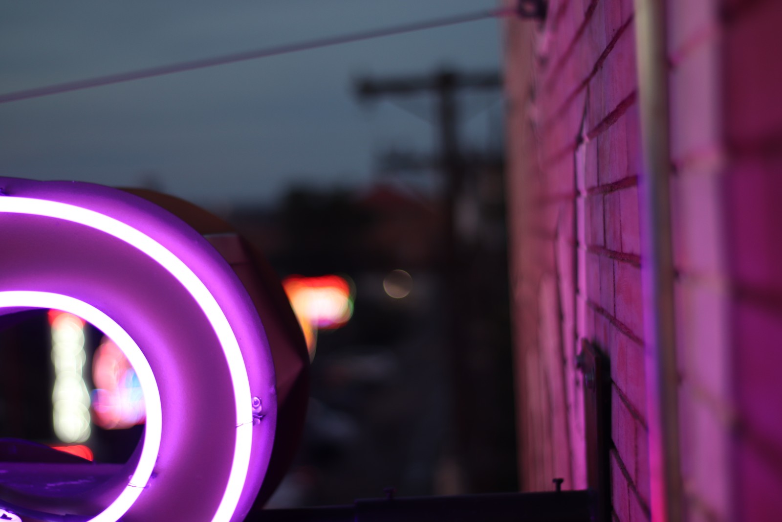 Purple neon sign on a brick wall in front of a building (pink, magenta, wheel, violet, tire)