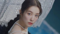 Irene from Red Velvet, showcasing an elegant look with pearls and a backdrop of shimmering details.