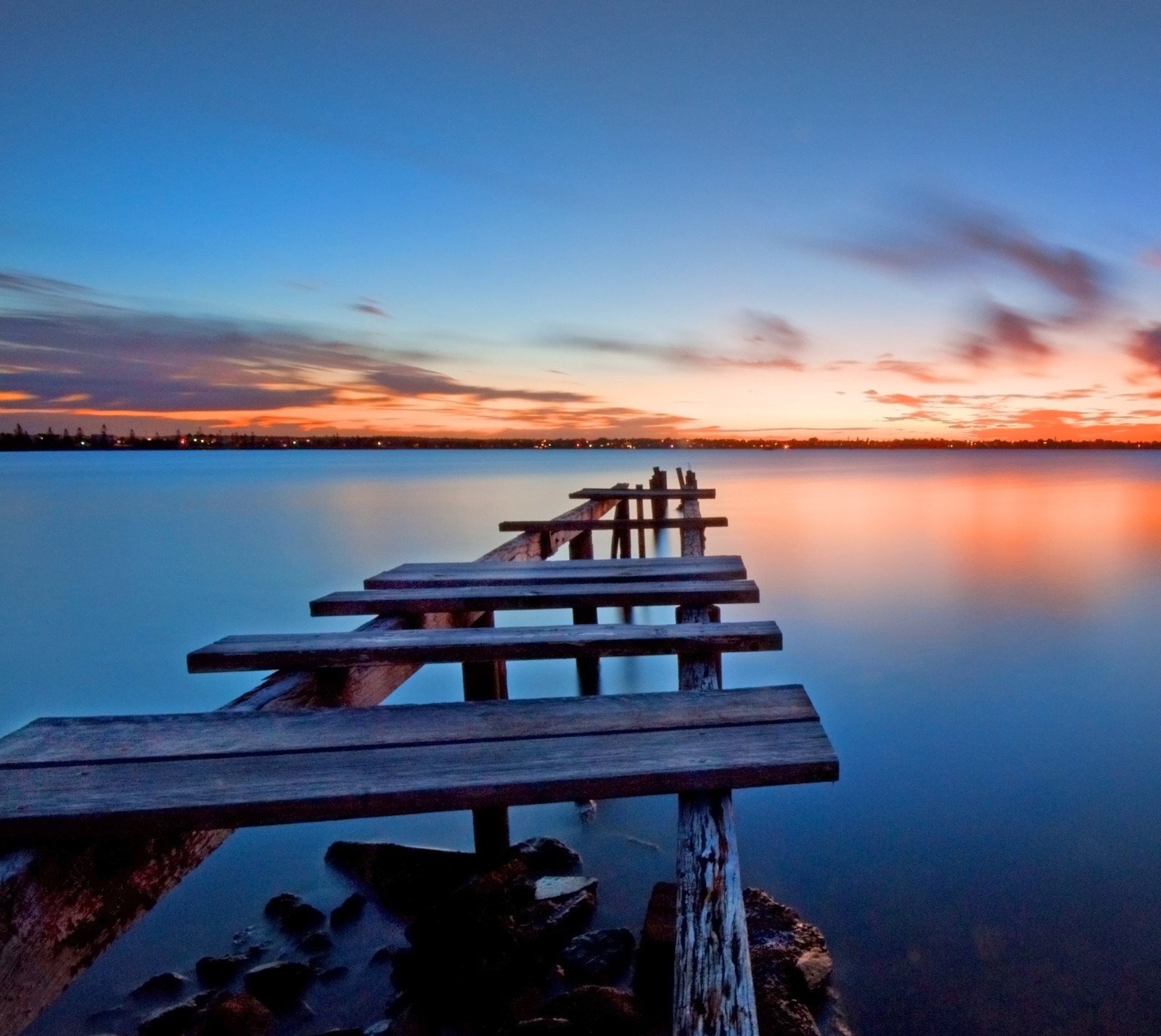 Une jetée en bois au milieu d'un lac au coucher du soleil (beau coucher de soleil, crépuscule)