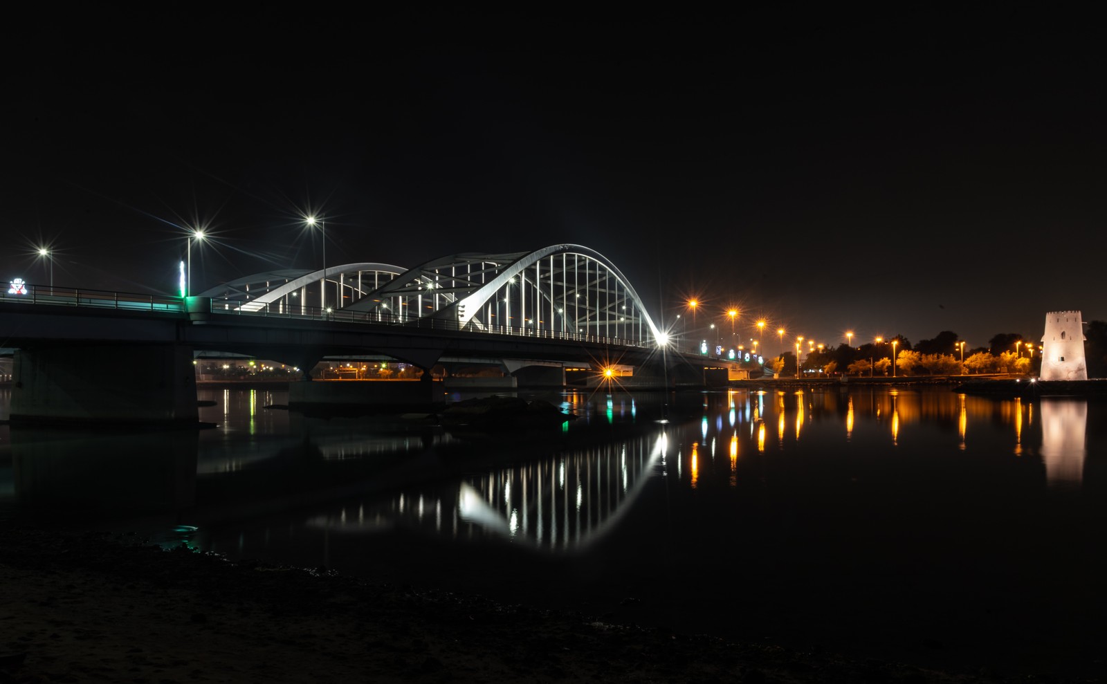 Vista aérea de uma ponte sobre um rio à noite com luzes refletidas na água (arquitetura, abu dhabi, noite, ponte, água)