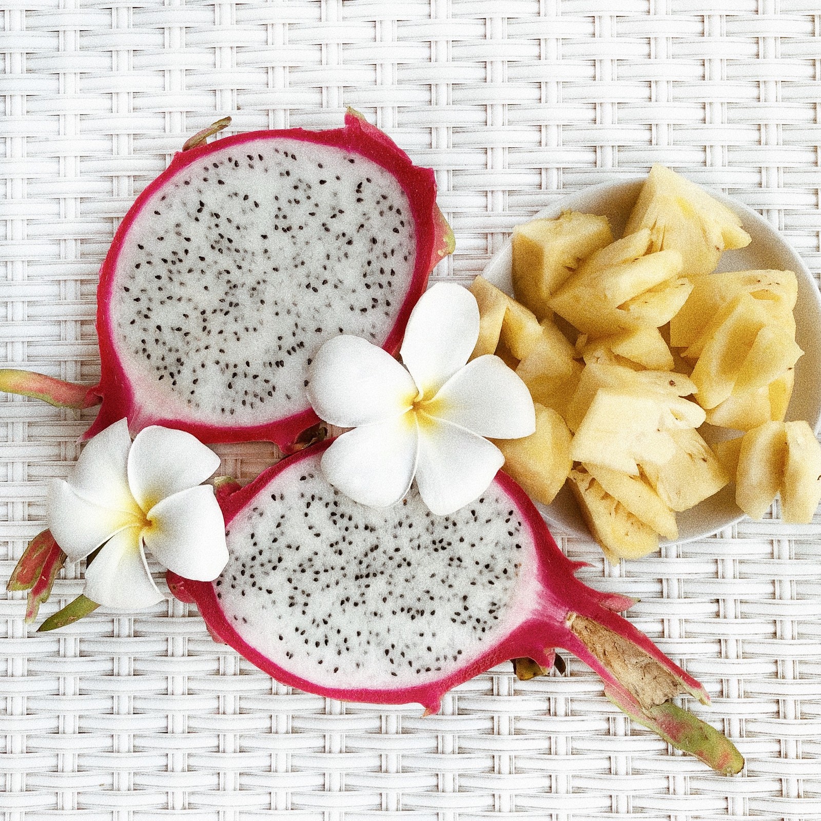 Une assiette blanche avec un fruit du dragon et des bananes tranchées (pétale, jaune, nourriture, plante à fleurs, fleurs coupées)