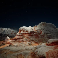 Paisagem montanhosa iluminada por estrelas com formações rochosas distintas