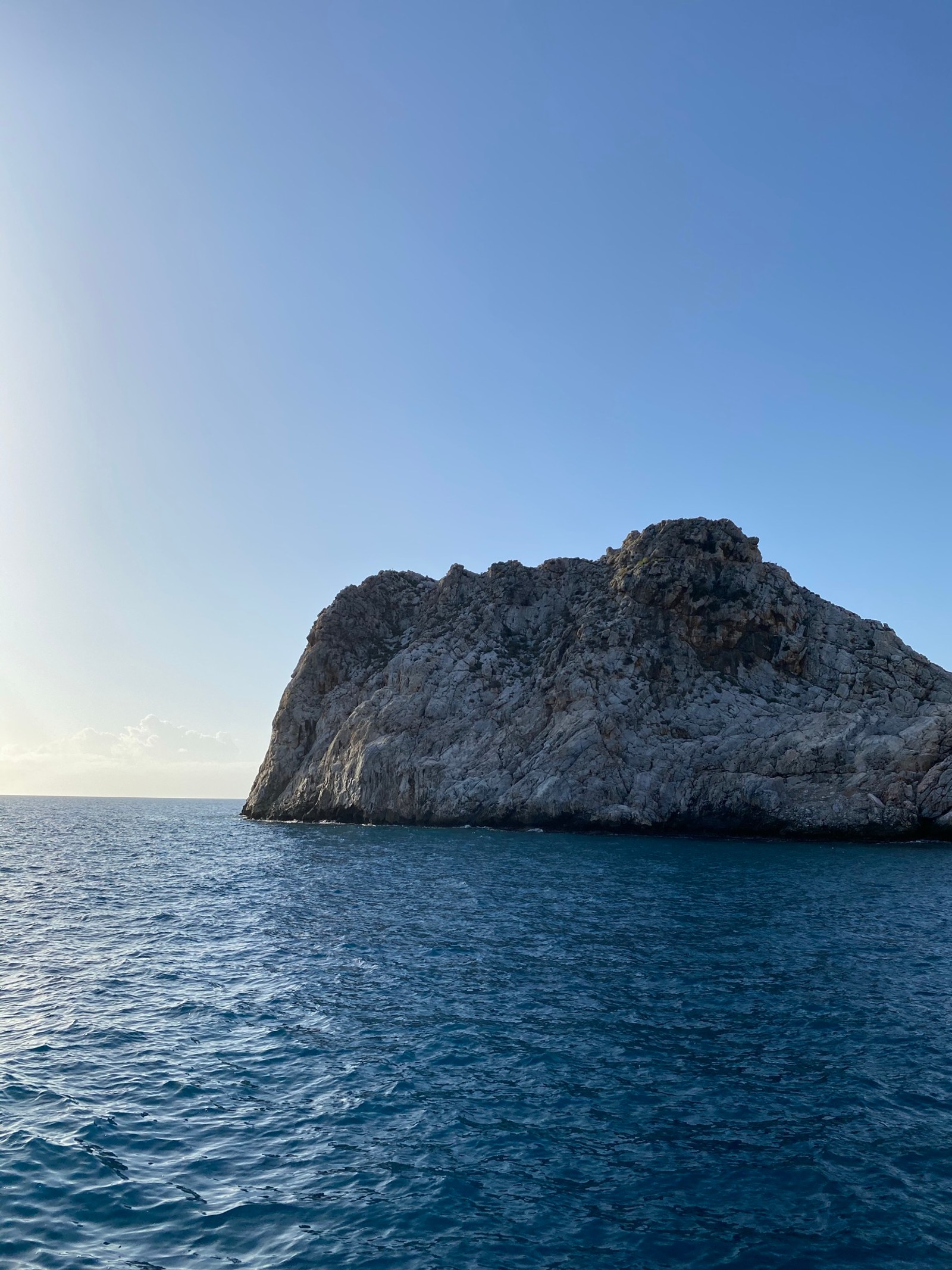 Una roca aislada en medio del océano con un cielo despejado (mar, agua, roca madre, lago, horizonte)