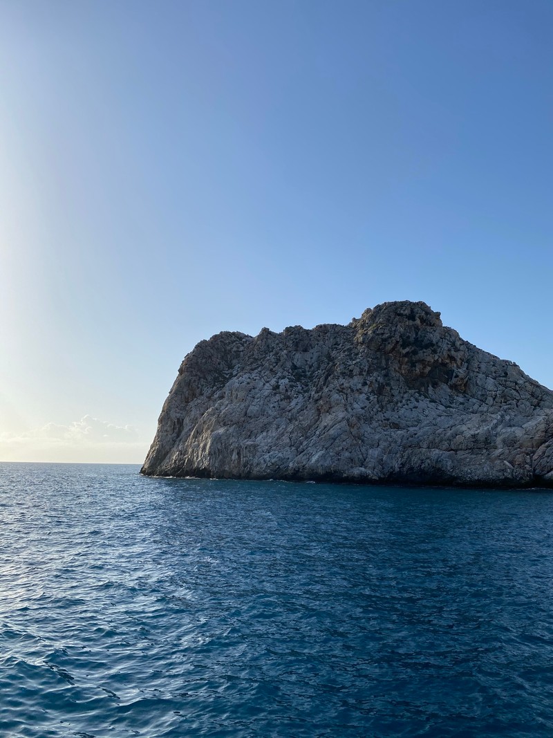 Скалистая гора посреди океана с ясным небом (море, вода, коренная порода, озеро, горизонт)