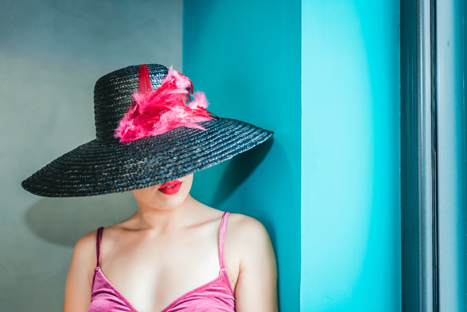 Mujer árabe en un vestido rosa y sombrero negro apoyada contra una pared (mujer, estadounidense, cami top, sombrero, femenino)