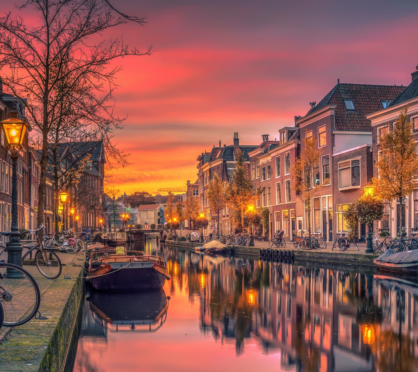 Vista aérea de um canal com barcos e edifícios ao pôr do sol (amsterdã, amsterdam, cidade, cor)