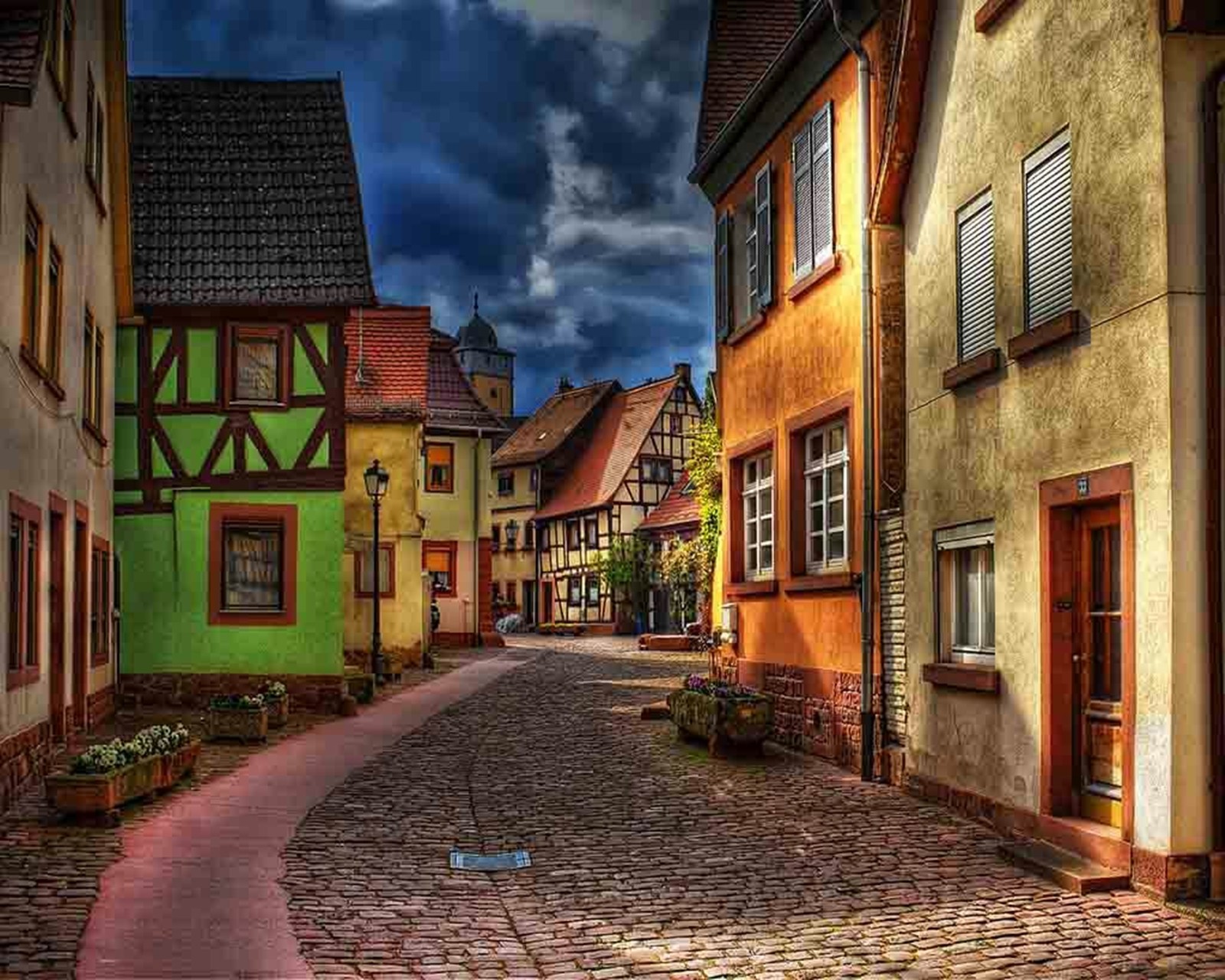 There is a cobblestone street with a cobble stone sidewalk (nice, street, view)