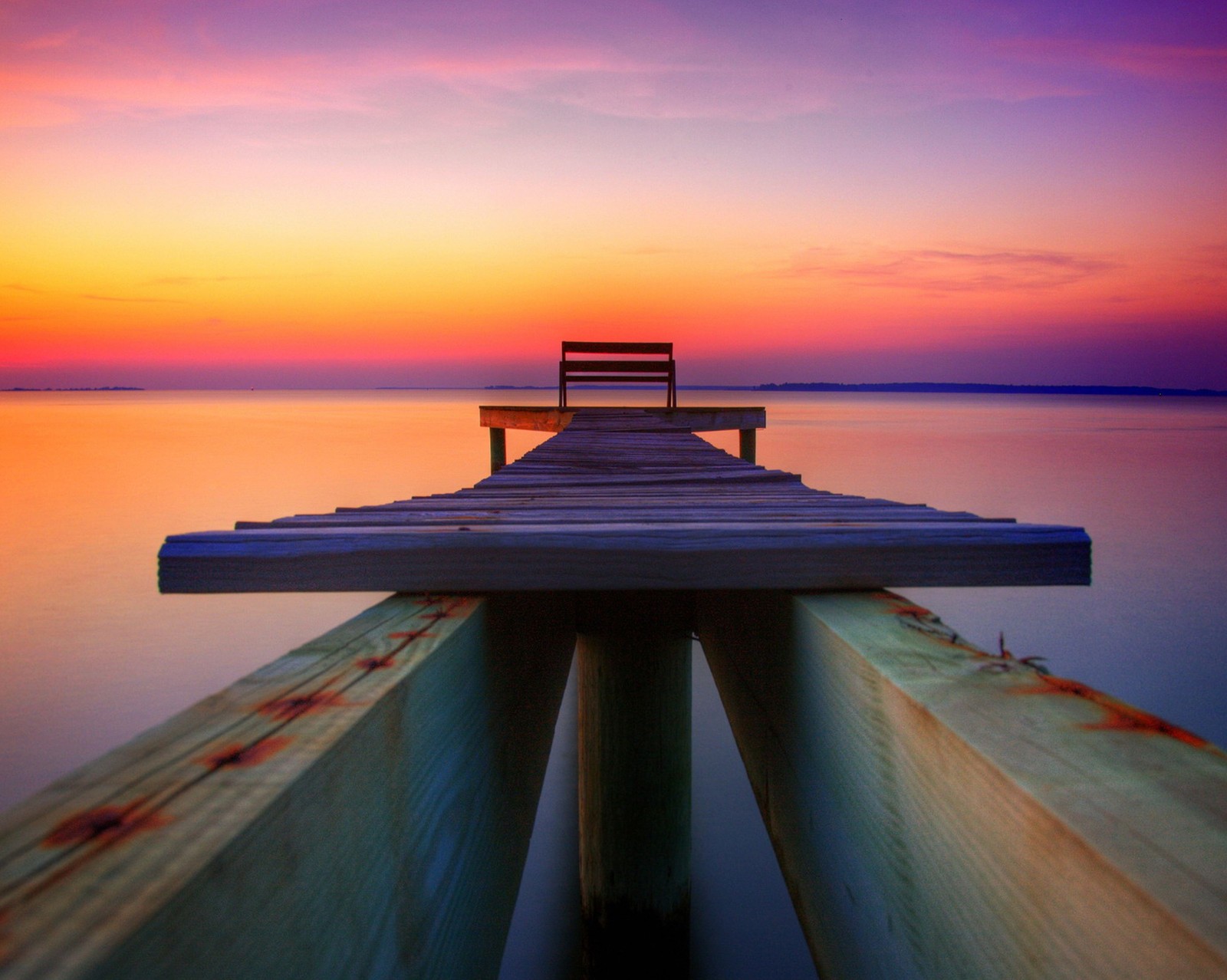 Un quai en bois arabe avec un banc au coucher de soleil (pont, paysage violet, route)