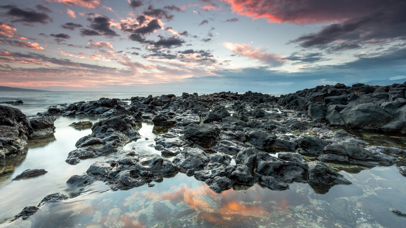 A sunset view of the ocean and rocks at low tide (water, rock, sea, reflection, shore)