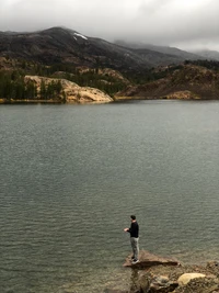 Pescador solitario en un tranquilo embalse de montaña