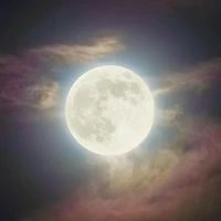 Super Pink Moon Illuminating Wispy Clouds in Night Sky