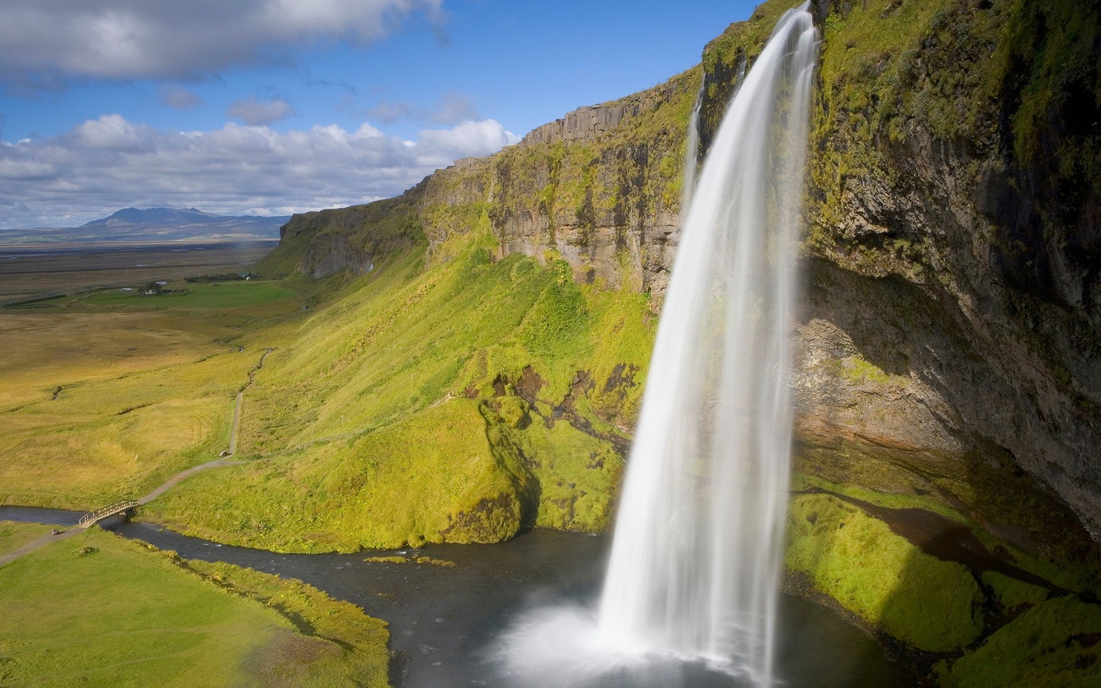 Ein wasserfall inmitten eines grünen tals mit einem fluss, der hindurchfließt (windows 7, microsoft windows, wasserfall, windows vista, betriebssystem)