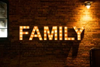 Illuminated 'Family' Sign Against a Rustic Brick Wall