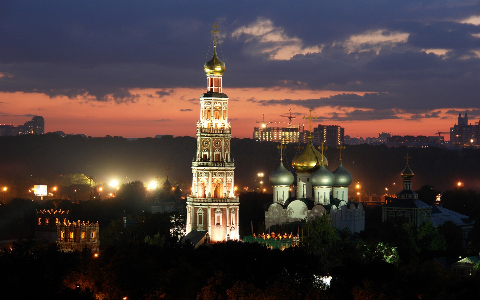 Vista noturna de uma grande igreja com uma torre de relógio no meio de uma cidade (torre, atração turística, marco, noite, cidade)