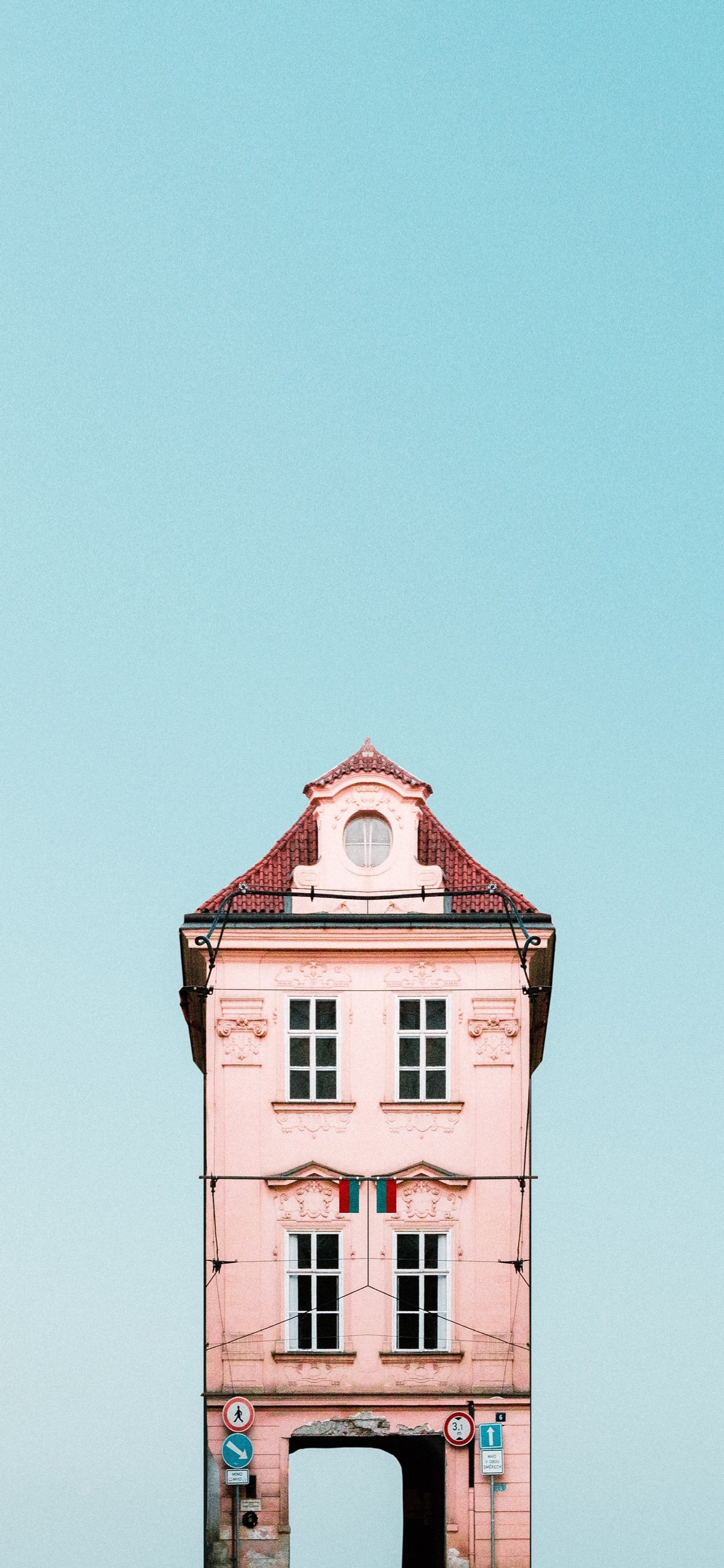 There is a pink building with a red roof and a red umbrella (window, tower, building, rectangle, brickwork)