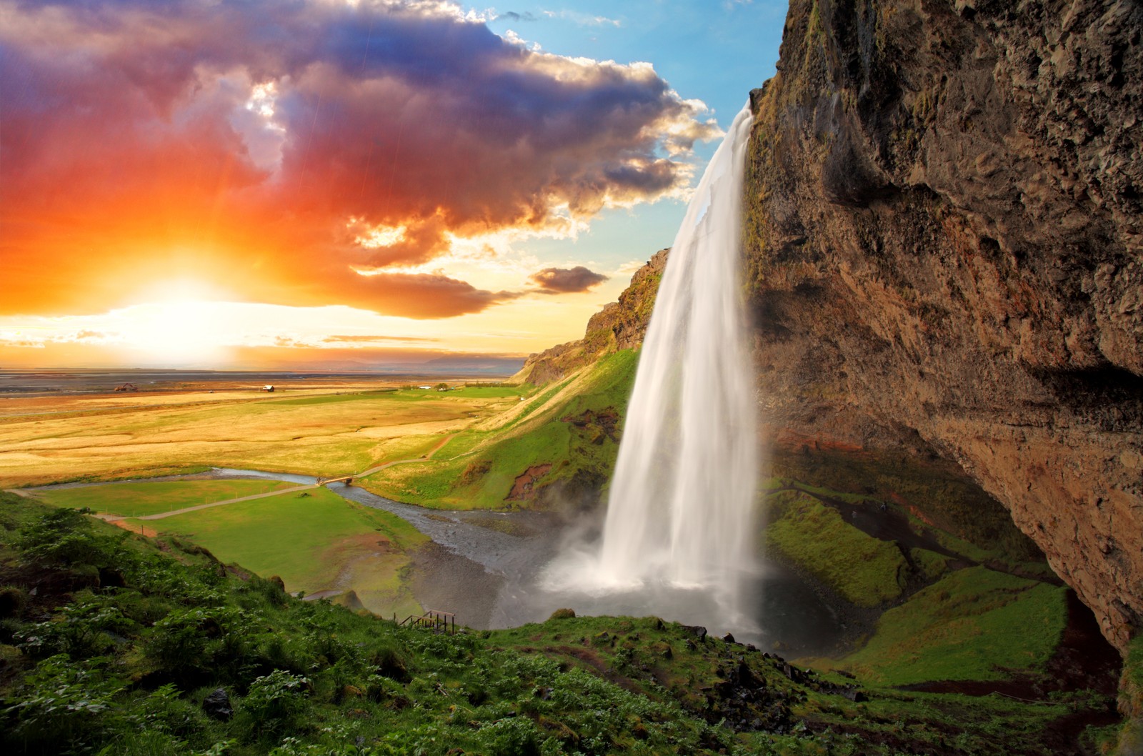 Uma cachoeira no meio de um vale verde exuberante com um pôr do sol (seljalandsfoss, cachoeira, paisagem natural, natureza, recursos hídricos)