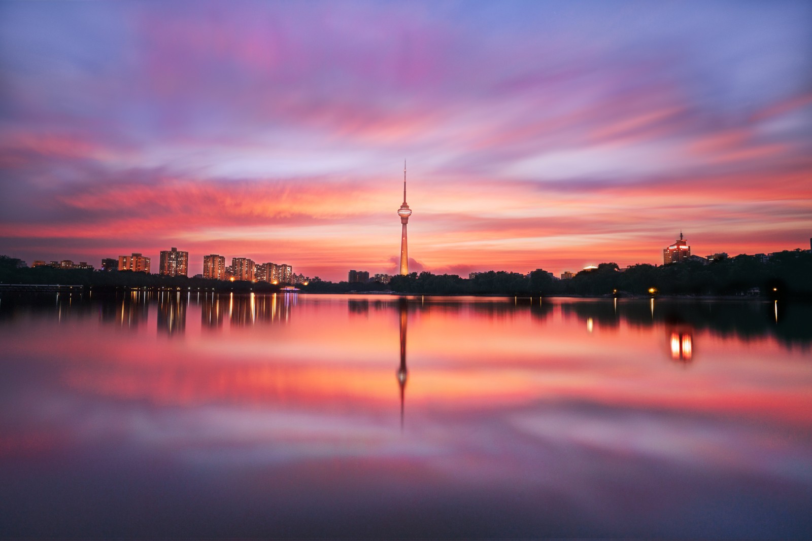 Uma vista do horizonte da cidade com um lago e uma torre (china central tv tower, pequim, china, corpo de água, silhueta)