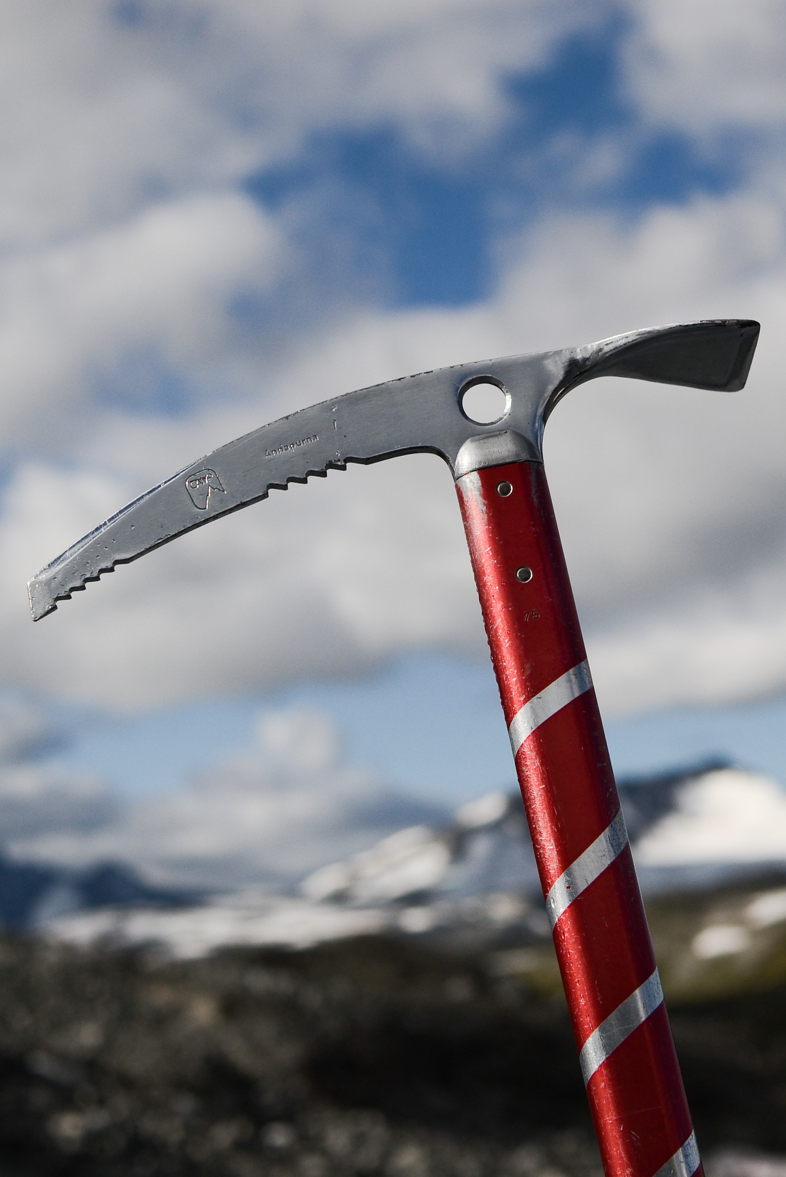 There is a red and white striped handle on a red and white pickle (climbing, hiking, ice axe, moutains, nature)