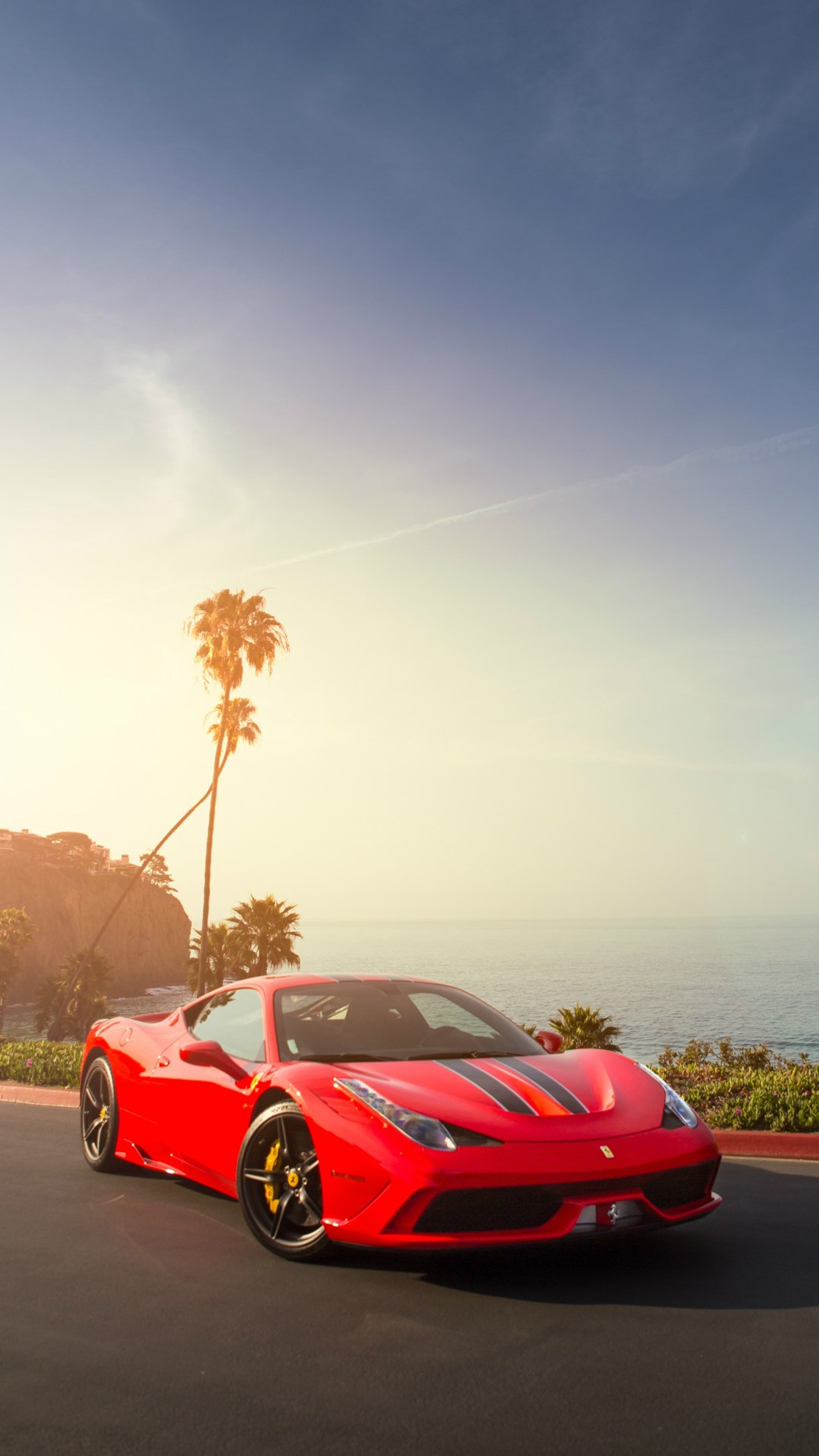 A close up of a red sports car driving on a road near the ocean (cars, ferrari, red, sports)