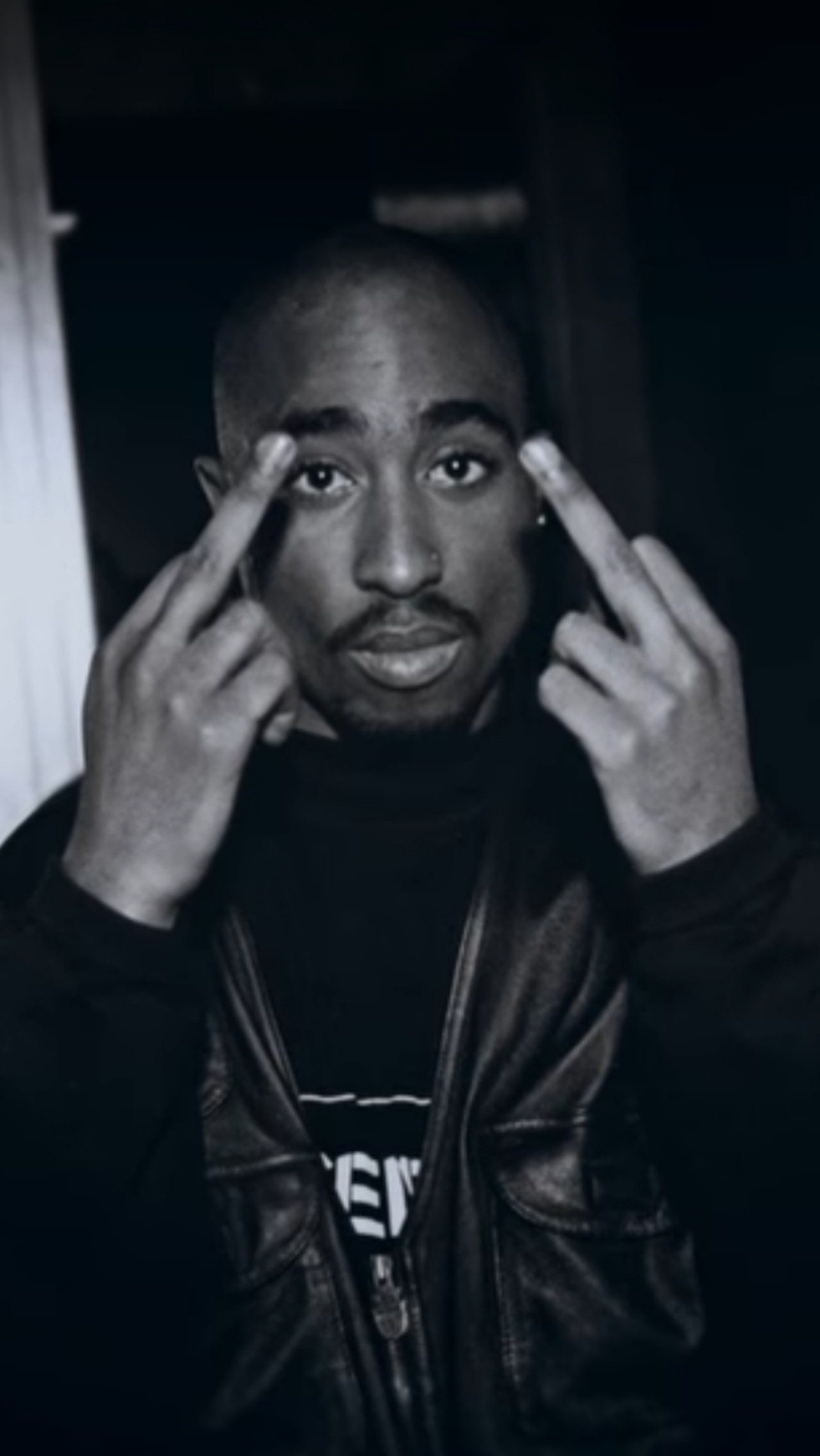 Un homme arafed en veste noire levantant les mains vers son visage (2pac, biggie, rap, tupac)