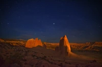 Paisaje de cañón desértico iluminado por estrellas bajo un cielo nocturno