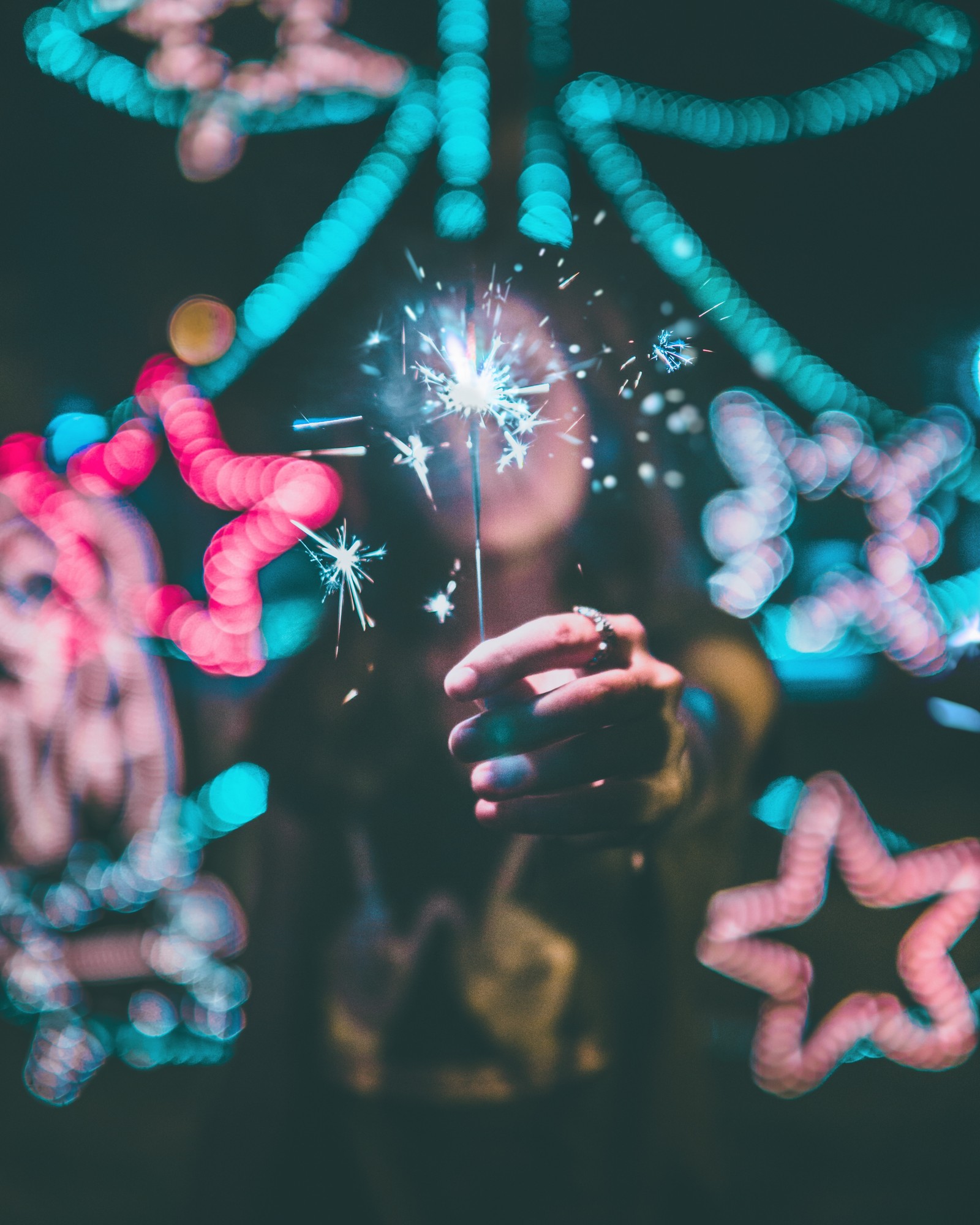 Alguien sostiene un chispero en su mano con muchas luces de fondo (ligero, rosa, evento, dedo, diversión)