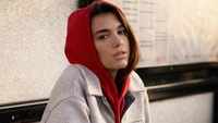 Dua Lipa dans une tenue décontractée avec un sweat à capuche rouge, dégageant confiance et style.