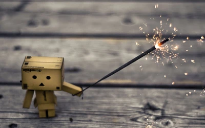 Danboard Robot Holding a Sparkler Against a Wooden Background