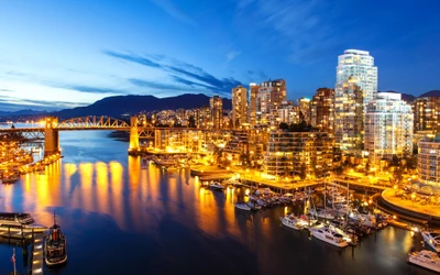 Paisaje urbano de Vancouver por la noche: horizonte iluminado y reflejos en la marina.