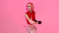 Cosplay de Sakura Haruno contra um fundo rosa, exibindo um gesto dinâmico e estética de anime.