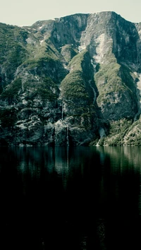 Majestätische Berge, die sich in einem ruhigen See mit einem versteckten Wasserfall spiegeln, Ardal, Norwegen