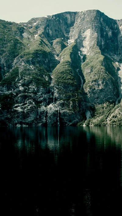 Montañas majestuosas reflejándose en un lago sereno con una cascada oculta, Ardal, Noruega