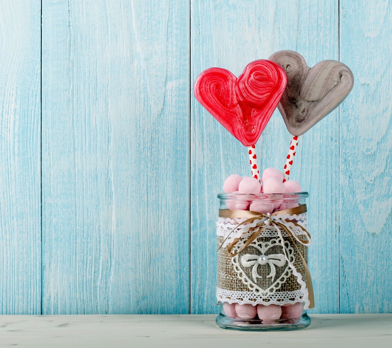 Il y a deux sucettes en forme de cœur dans un bocal sur une table (bonbons, cœur, amour, paire)