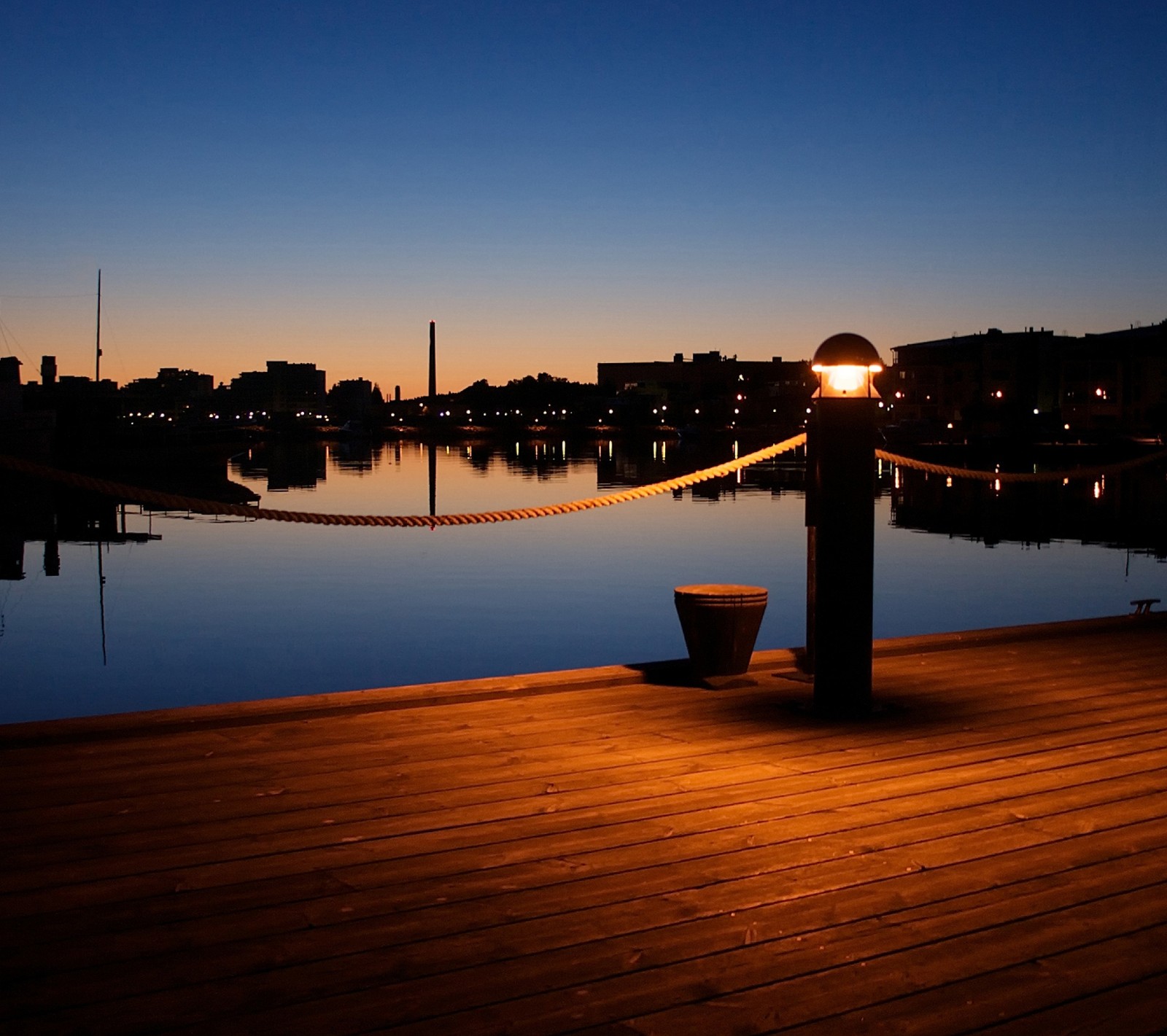 Há um vaso em um cais com uma luz acesa (paisagem, luz, noite, cais, mar)