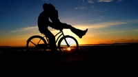 Silueta de una pareja compartiendo un beso romántico en una bicicleta al atardecer