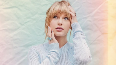 Taylor Swift con un suéter azul claro, posando pensativa con un fondo suave.