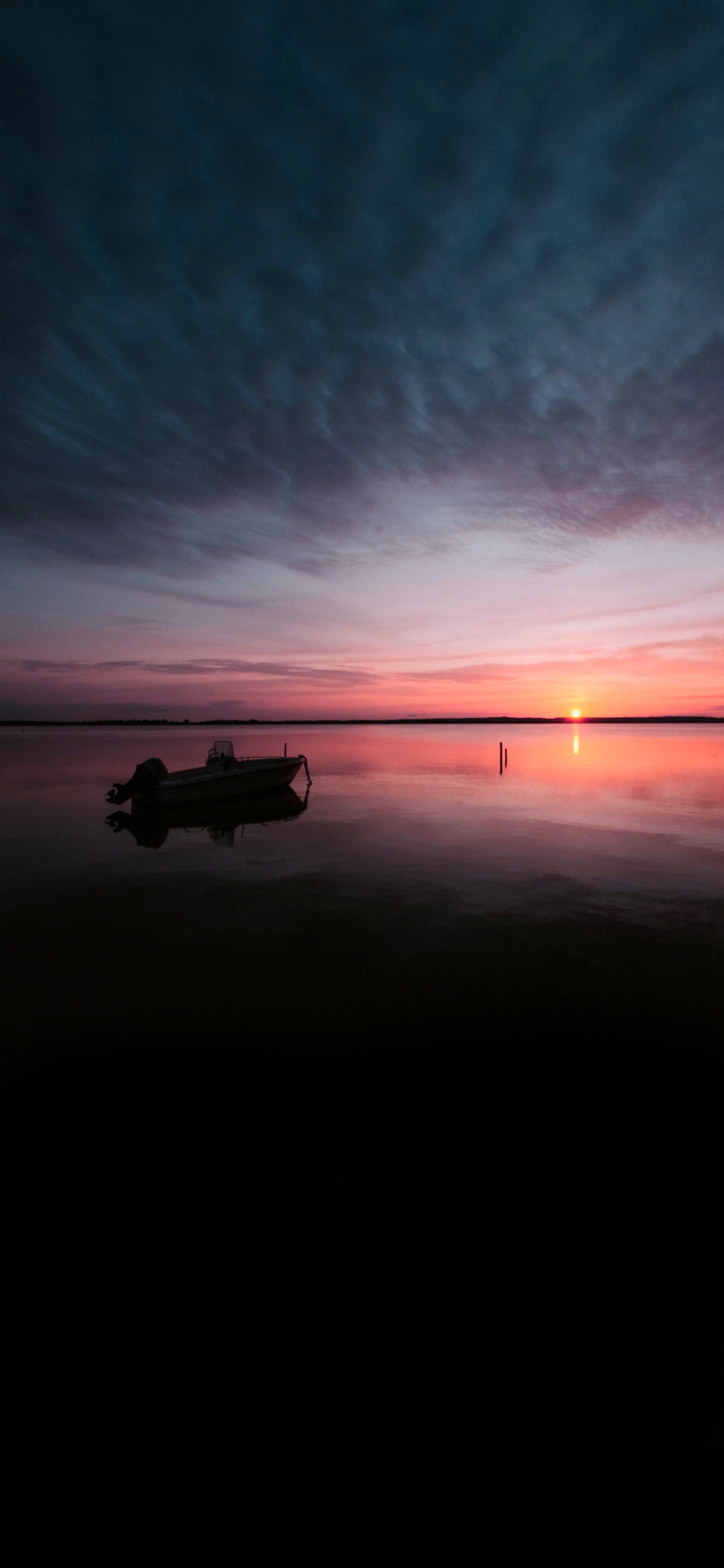 There is a small boat that is sitting on the water (cloud, water, atmosphere, afterglow, dusk)