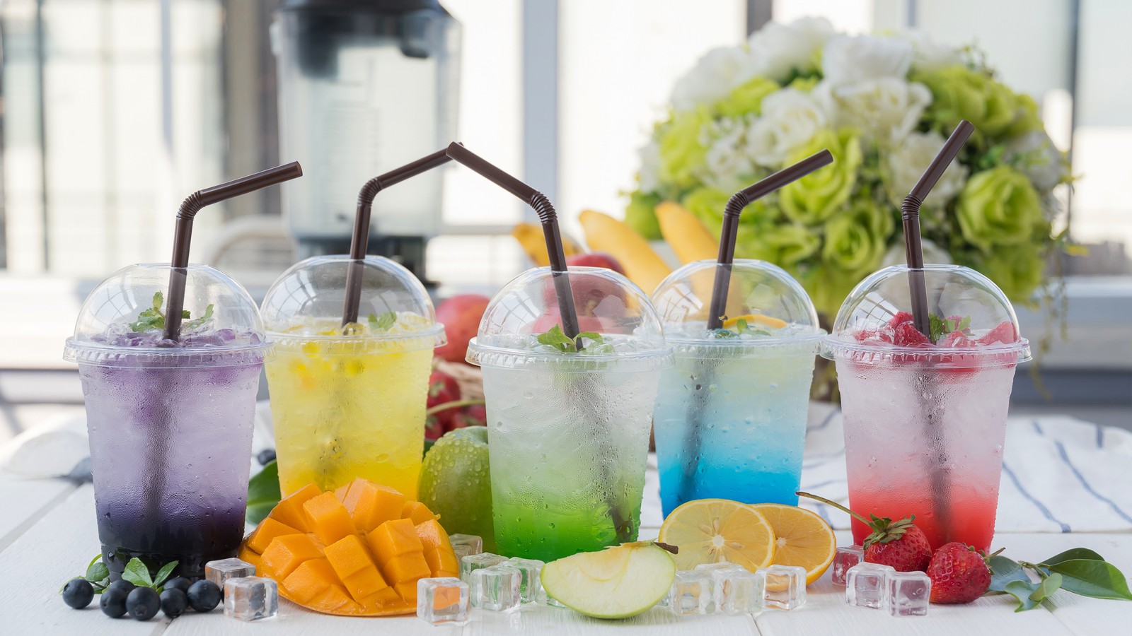 Several different colored drinks with straws and fruit on a table (milkshake, juice, drink, tableware, cocktail)