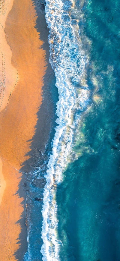 Serene Küstenwellen: Luftaufnahme des blauen Ozeans, der auf den goldenen Sand trifft