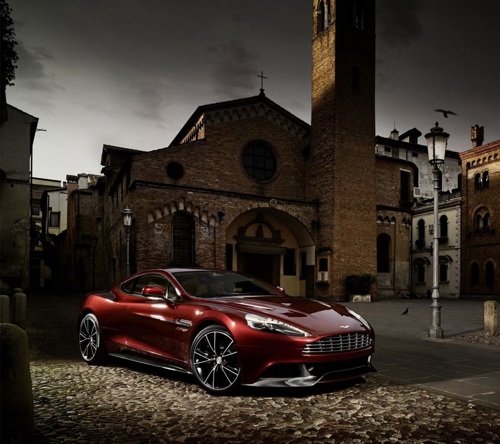 Un primer plano de un coche rojo estacionado frente a una iglesia (aston martin, coche, kola)