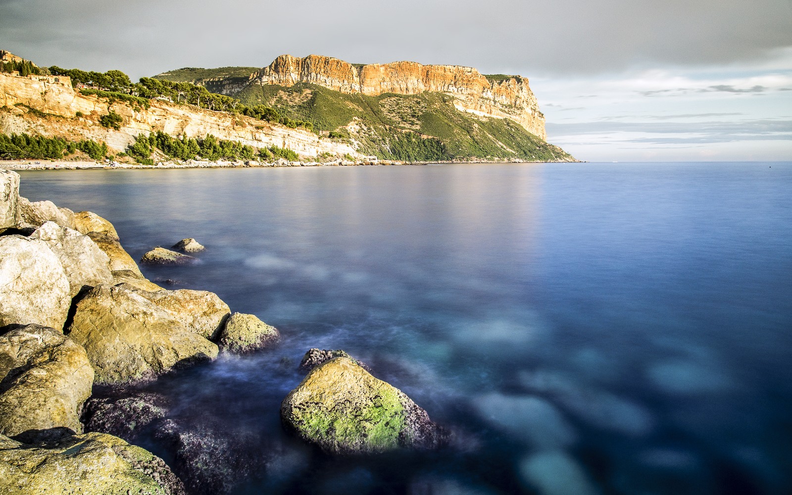 Una vista de una costa rocosa con una montaña a lo lejos (cap canaille, francia, mar mediterráneo, cabecera, acantilado)